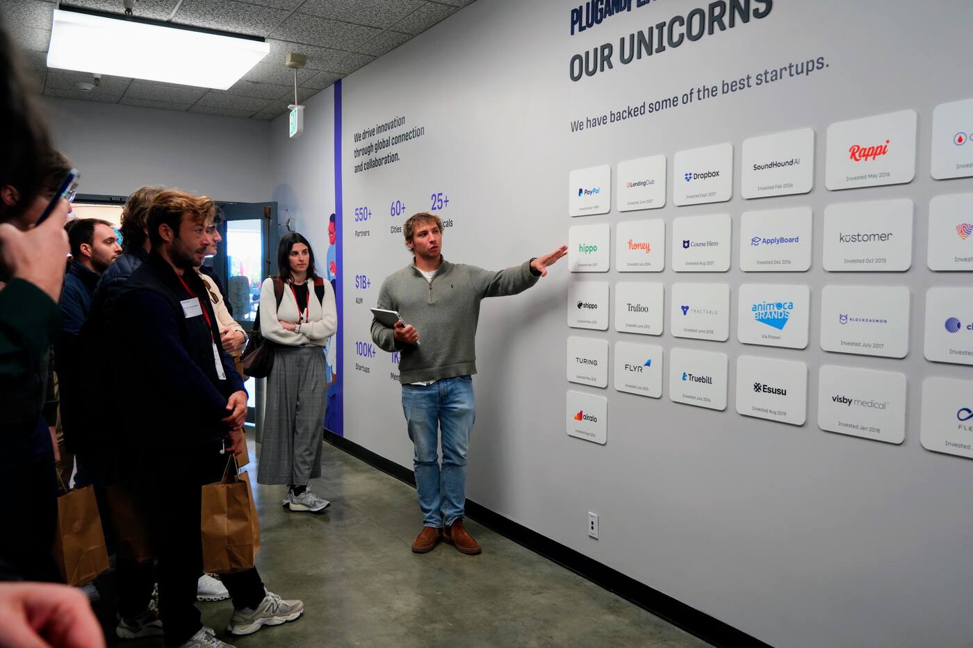 Tour in front of a wall of unicorn logos