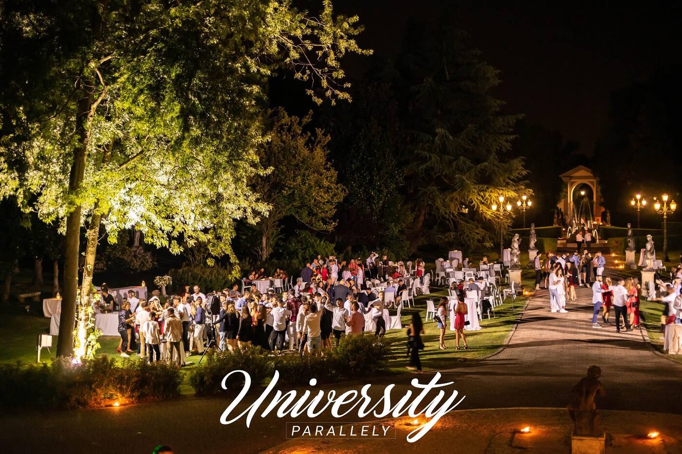 Hundreds of guests at a night dinner in a villa garden