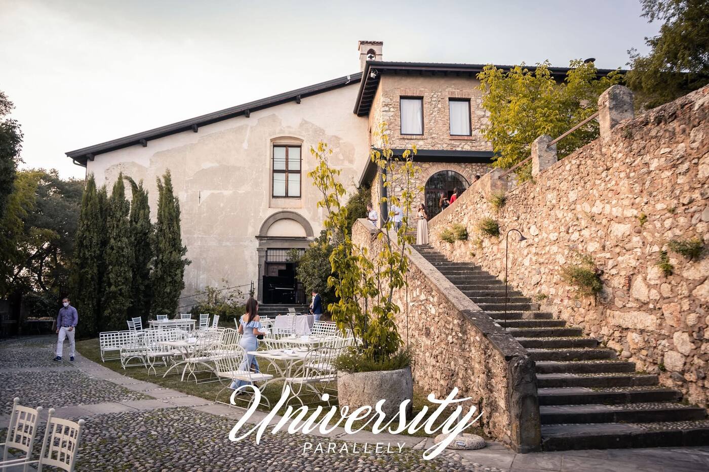 Tables set below a stone villa staircase