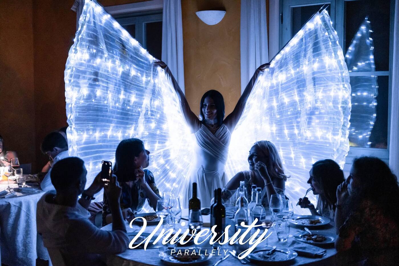 Performer with illuminated wings above dinner guests